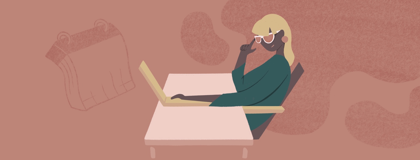 Woman sitting at desk with orange tinted sunglasses on, pointing at them and smiling.